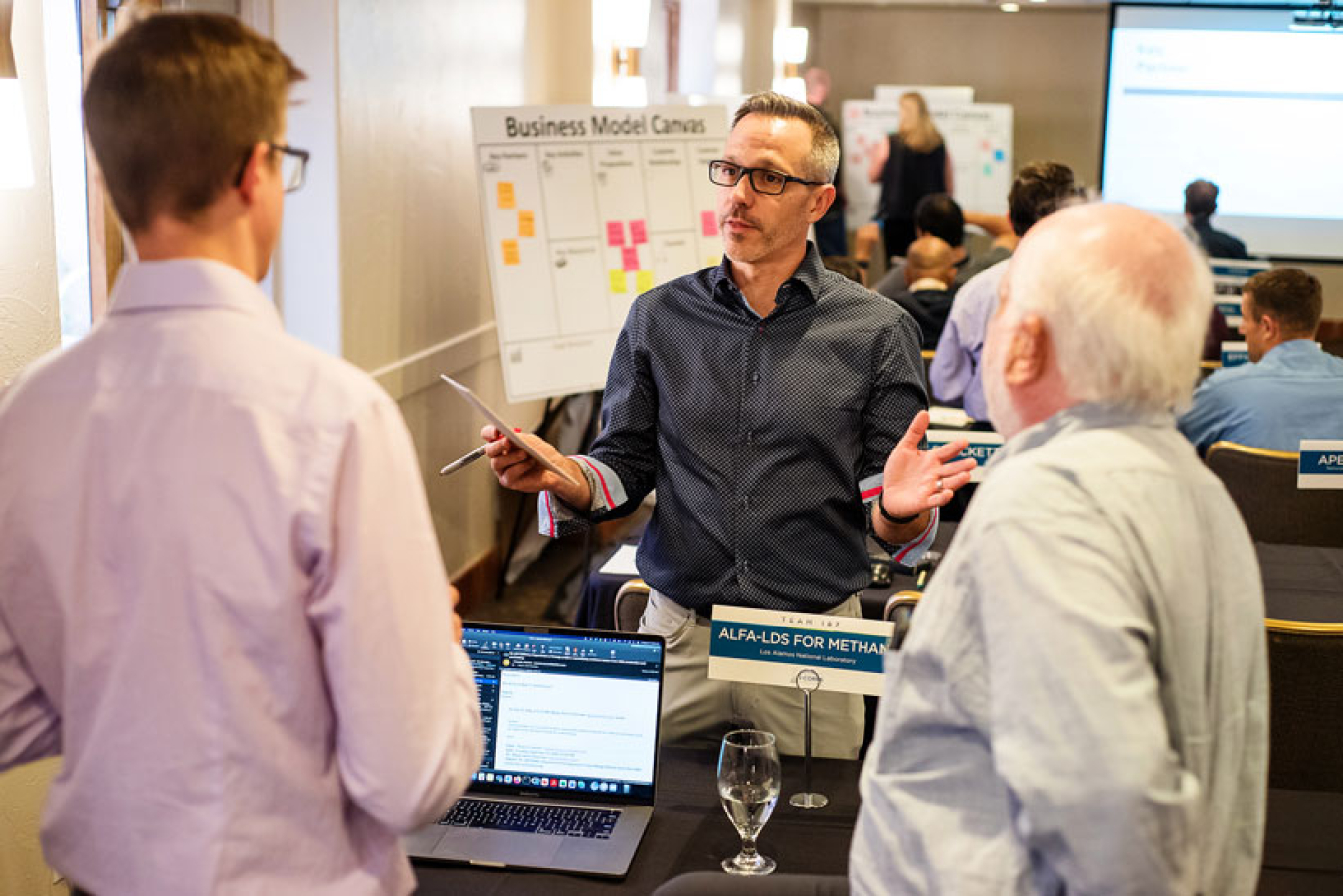 A trio of people talk candidly in a meeting room.