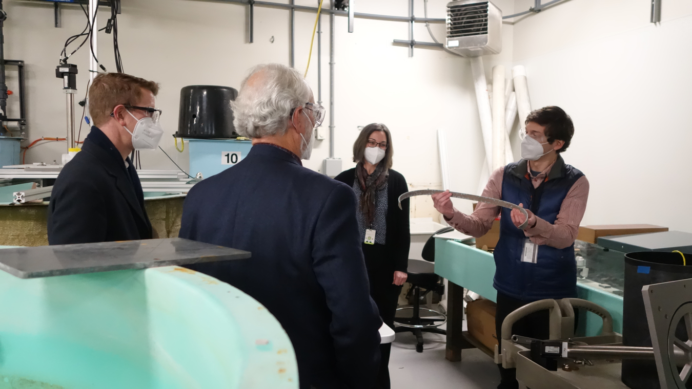 Person holding a rusted piece of material and speaking to three other individuals