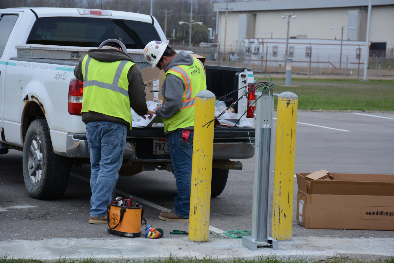 Workers at EM’s Portsmouth Site assemble parts to a new electric vehicle charging station outside the X-1000 Administration Building.