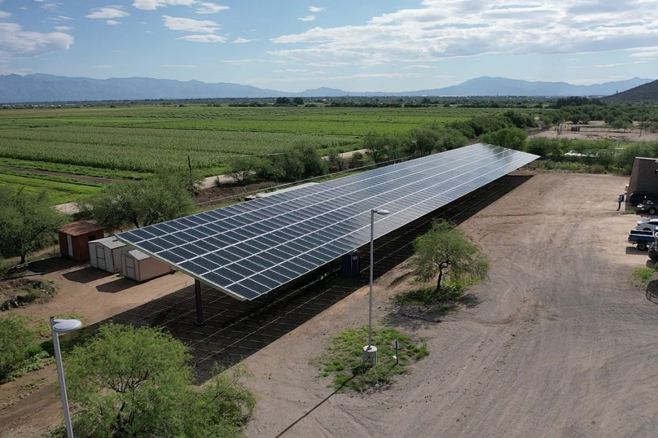 A large solar panel in a parking lot with fields in the background.