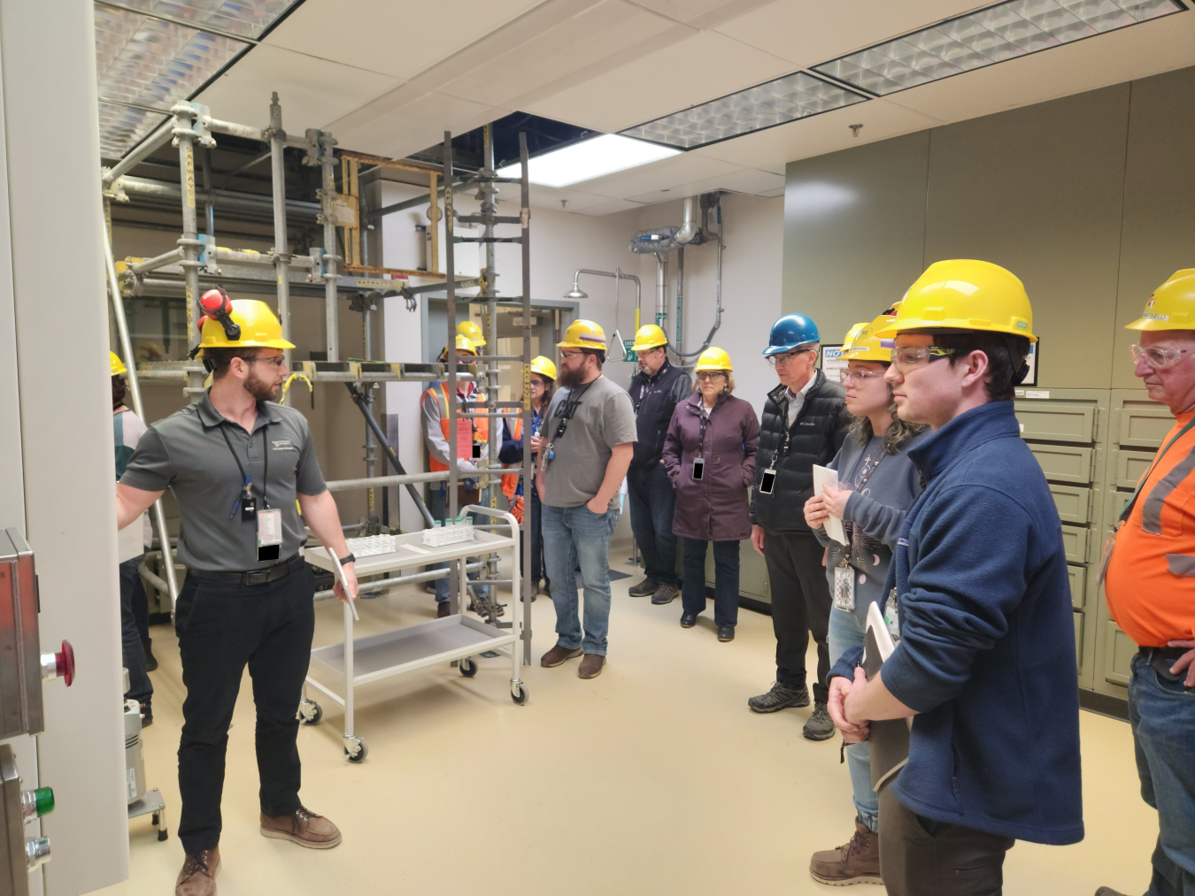 Waste Treatment and Immobilization Plant Shift Operations Supervisor Gent Ferati, left, gives EM Office of River Protection and Richland Operations Office Manager Brian Vance, fourth from right, an update on the status of an autosampling system at the plant.