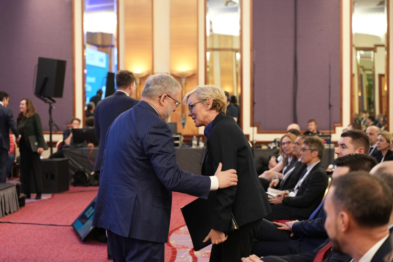 Ukraine's Minister of Energy German Galushchenko puts his hand on U.S. Secretary of Energy Jennifer Granholm's arm in a conference room during an event in Croatia.