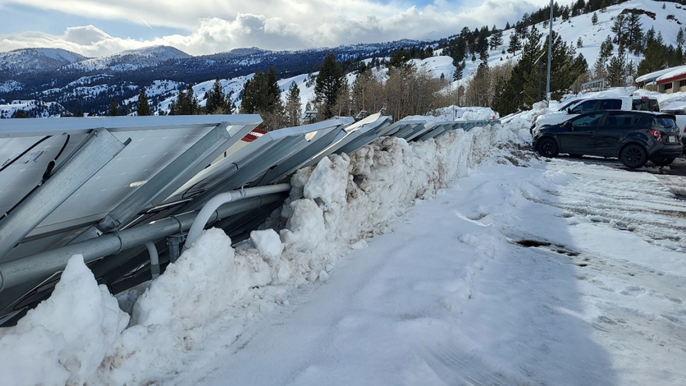 Damaged ground solar panels surrounded by snow.