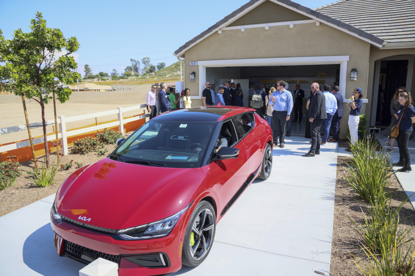 A sportscar in the paved driveway in front of a residence's garage.