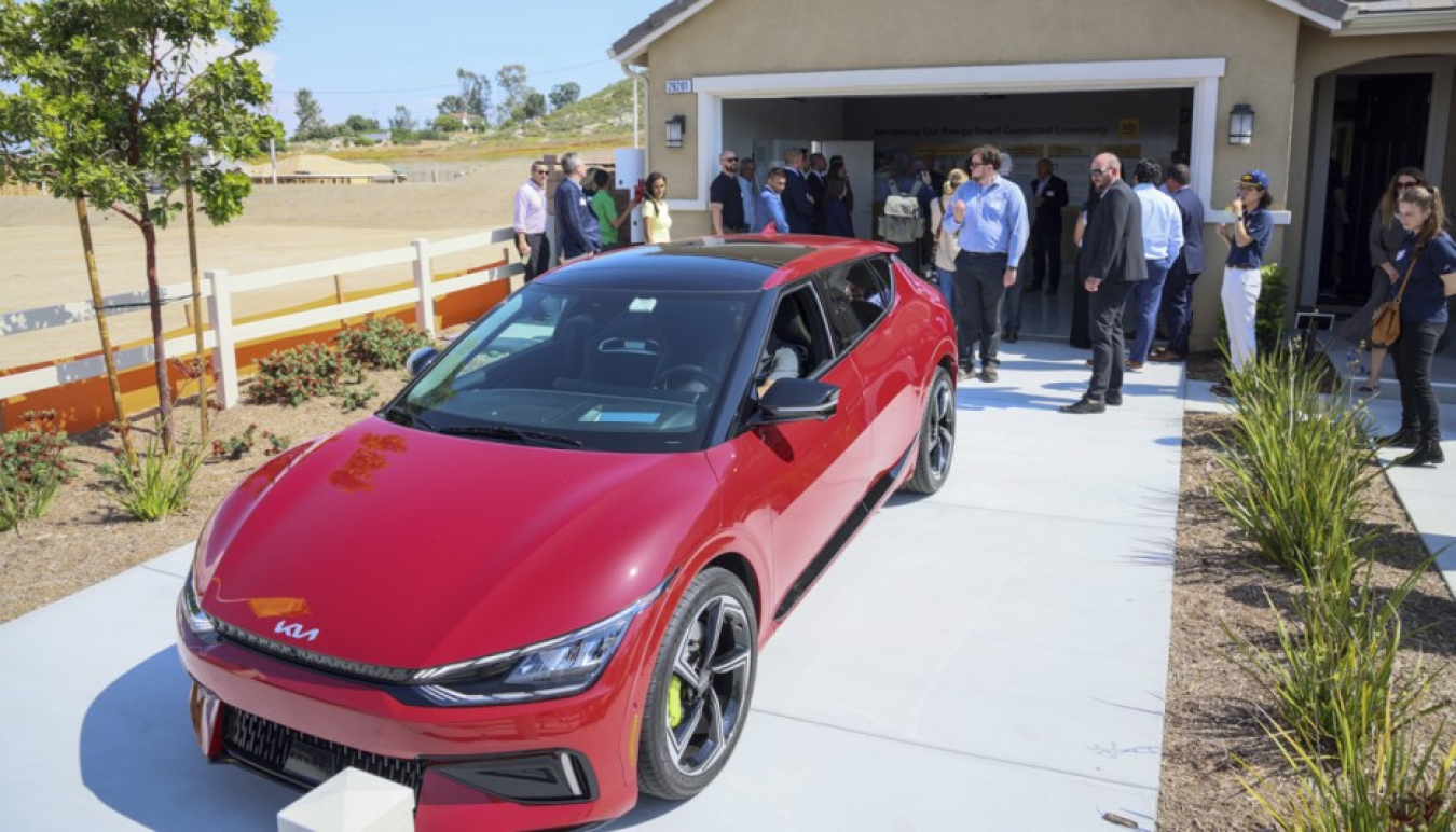 A sportscar sitting in the paved driveway in front of a residential garage.