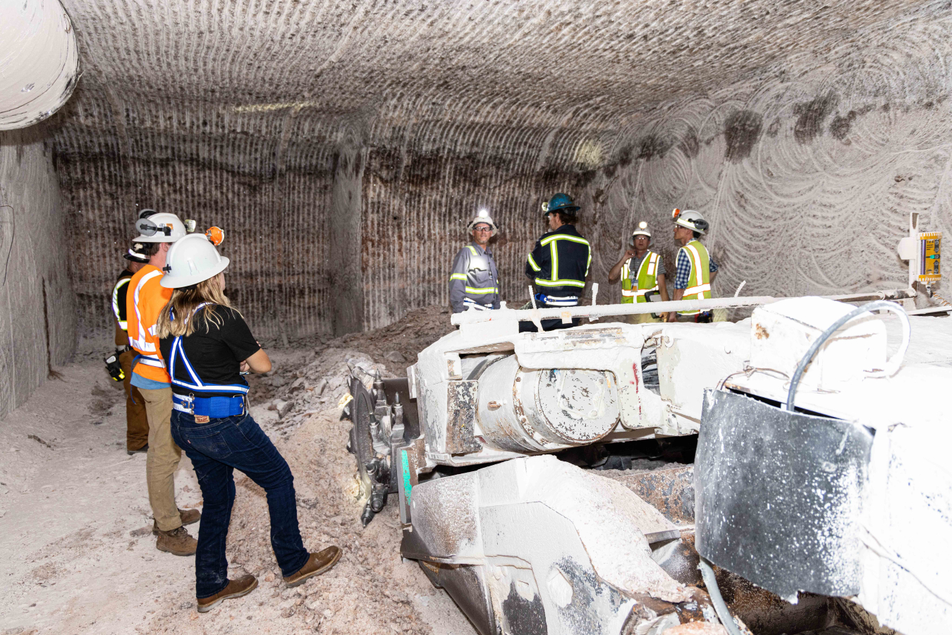 Waste Isolation Pilot Plant (WIPP) mining crews view progress in an ongoing mining tunnel, known as a drift, at the underground repository where a new utility shaft will eventually be connected. Excavation crews recently reached a milestone at the new utility shaft by reaching the depth necessary that allows horizontal tunneling work to begin on connecting the shaft to the WIPP underground complex.