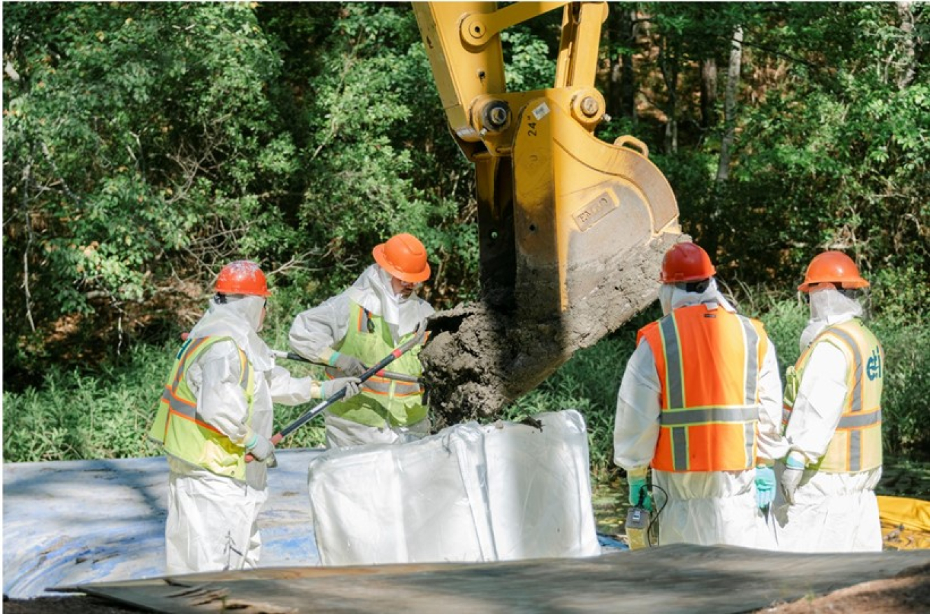 Workers place contaminated sediment from the excavation area for the Lower Three Runs project into sacks for disposal.