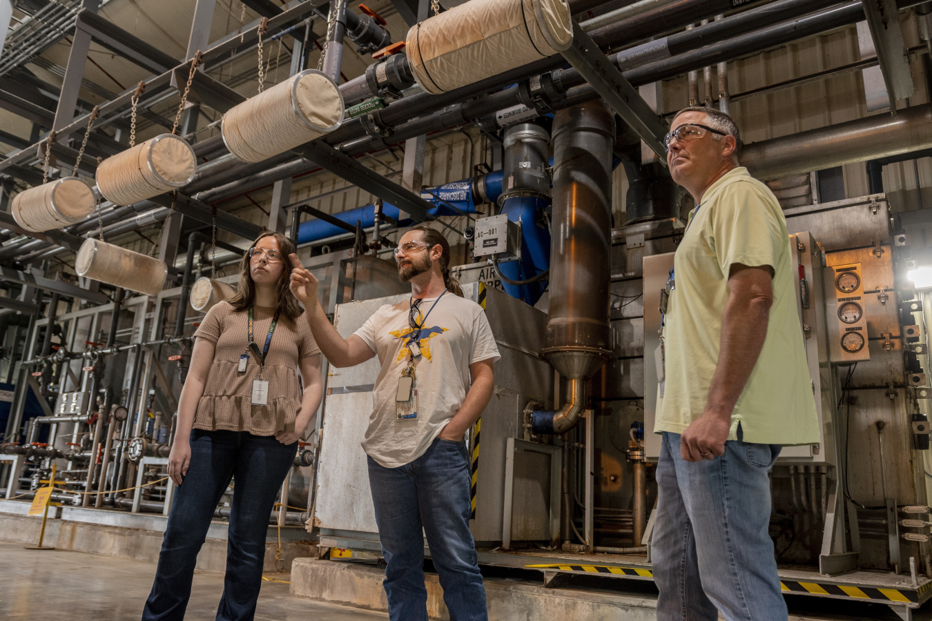 Environmental remediation workers at the Paducah Site inspect groundwater treatment equipment at the C-612 Northwest Pump-and-Treat facility. The C-612 facility was constructed in the early 1990s and was upgraded with modernized equipment in 2016, improving the reliability of the system and the efficiency of maintenance.