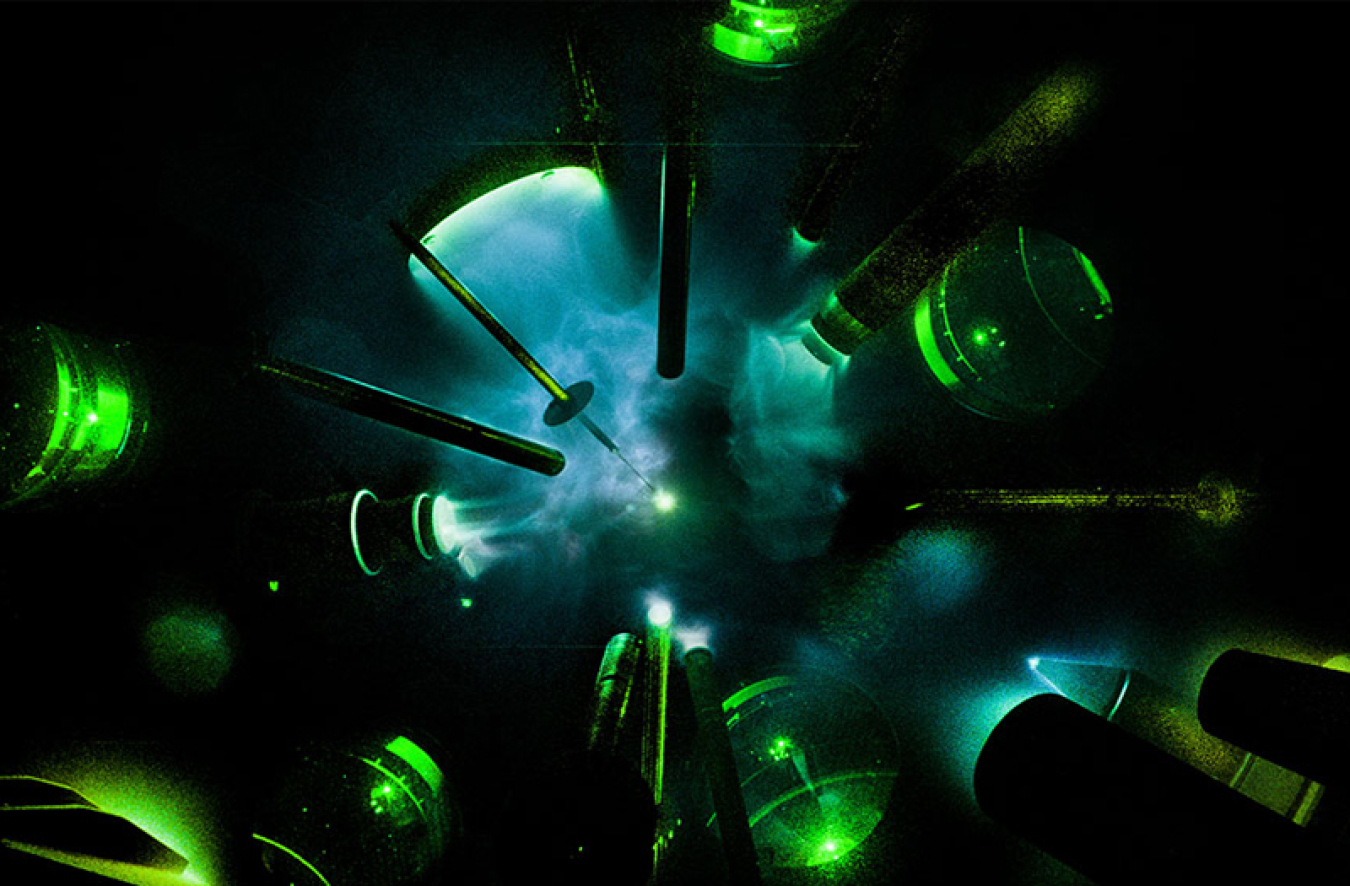 Image of lasers glowing green and shooting at a tiny glowing blue ball in the middle 