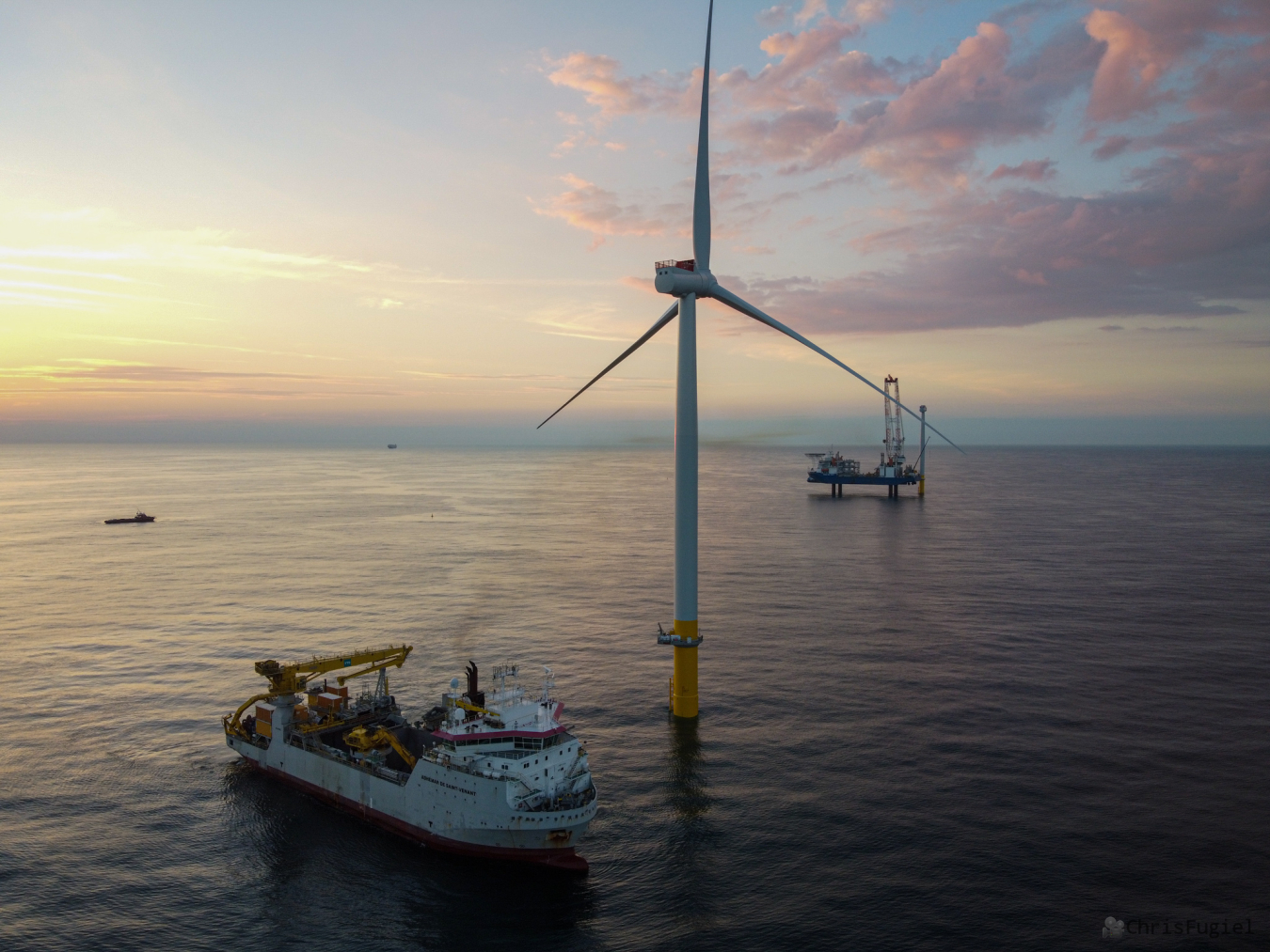 A wind turbine installation boat floats near a wind turbine in the ocean