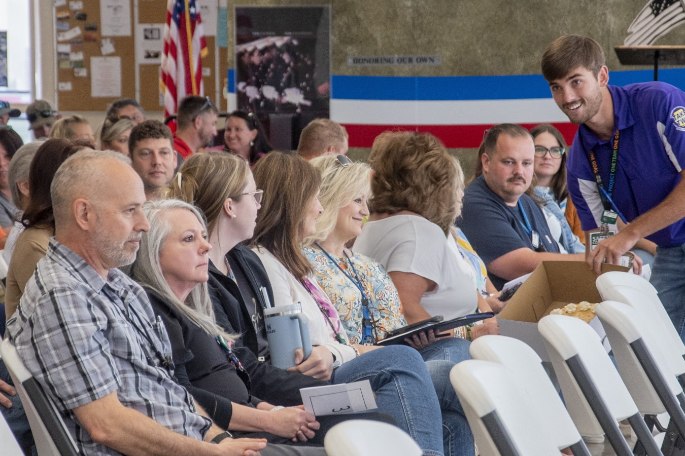 Four Rivers Nuclear Partnership Intern Andrew “Cole” Bobo, right, entices auction attendees with displays of cakes, pies and other baked goods donated to support the Feds Feed Families program this summer.