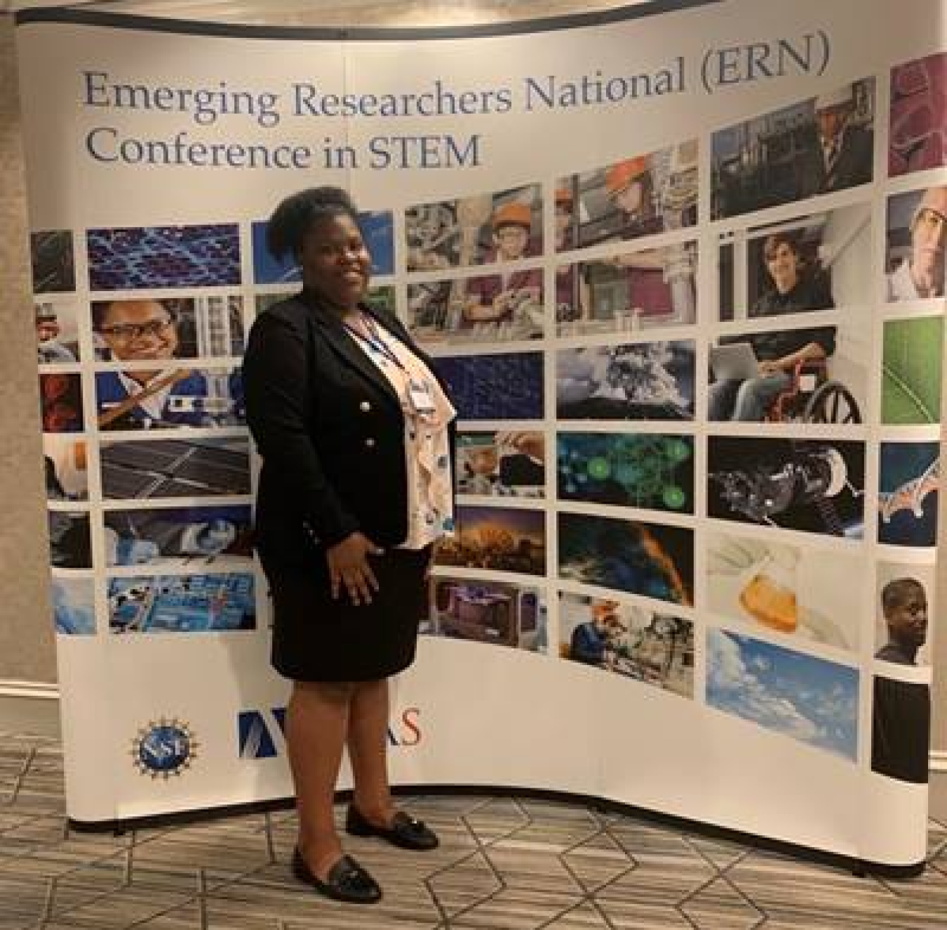 Lauri Kight standing in front of a sign with photos that says "Emerging Researchers National (ERN) Conference in STEM"