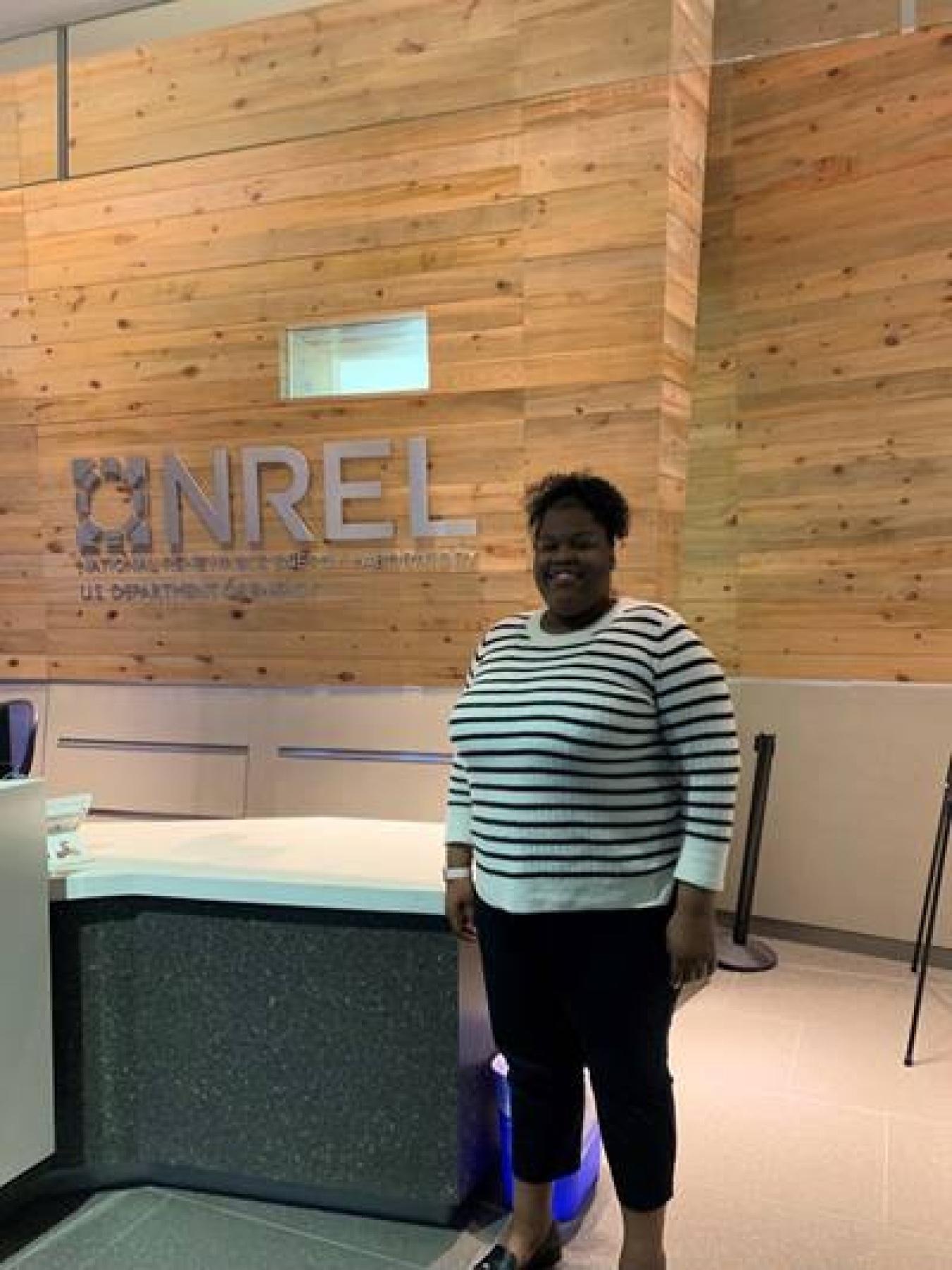 Lauri Kight standing in front of an NREL sign