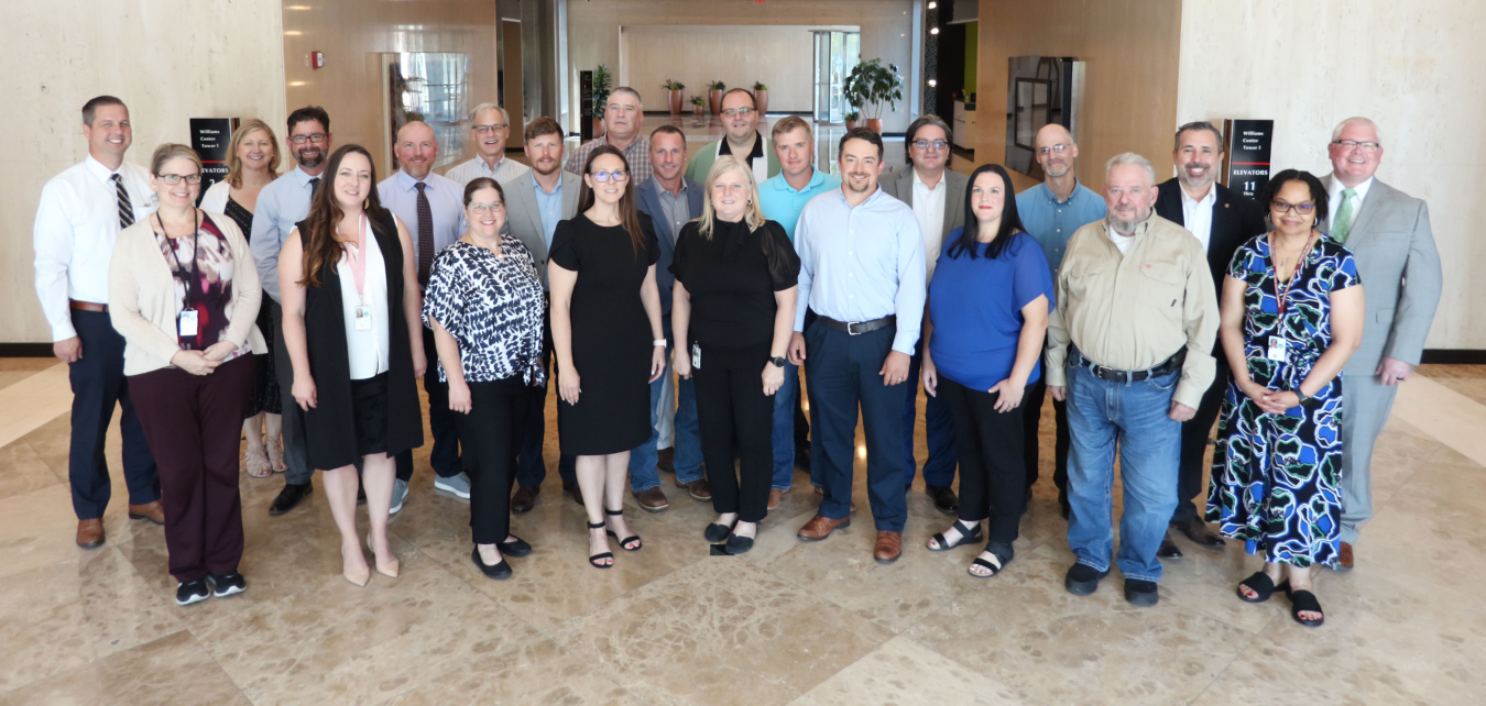 Group of Leadership Development Program Graduates. About 20 people posing in a line in a sunny building lobby.