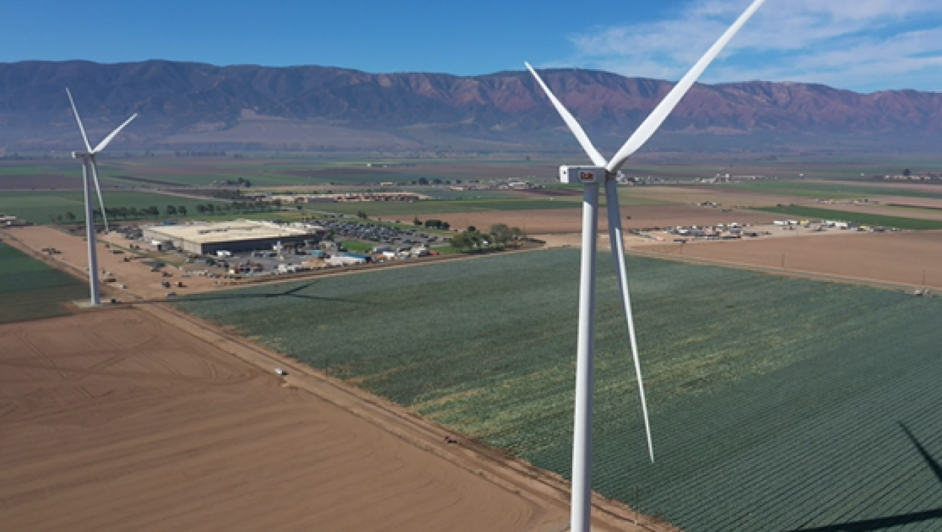 Two wind turbines in a large, open field.