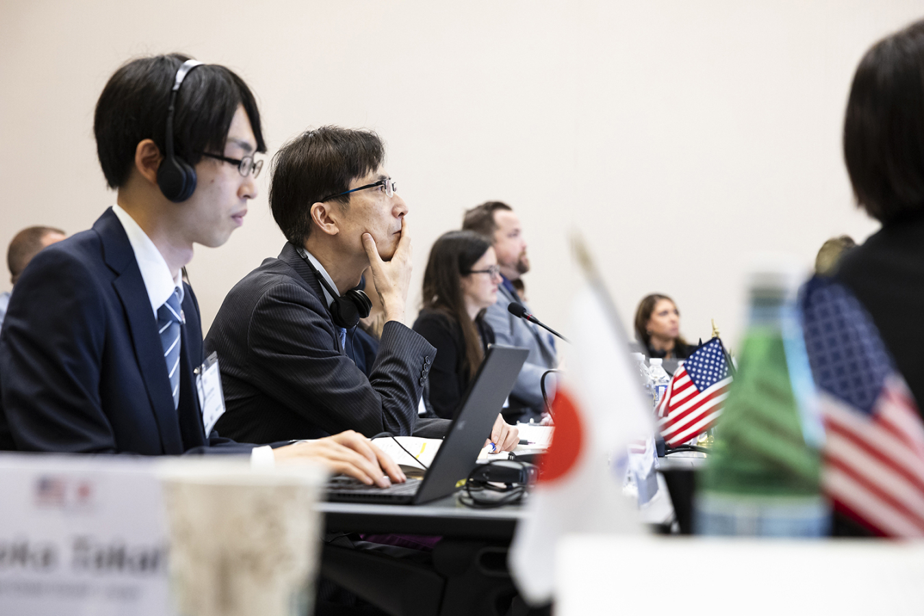 A young man types at a computer during the conference. Small Japanese and U.S. flags are in the foreground