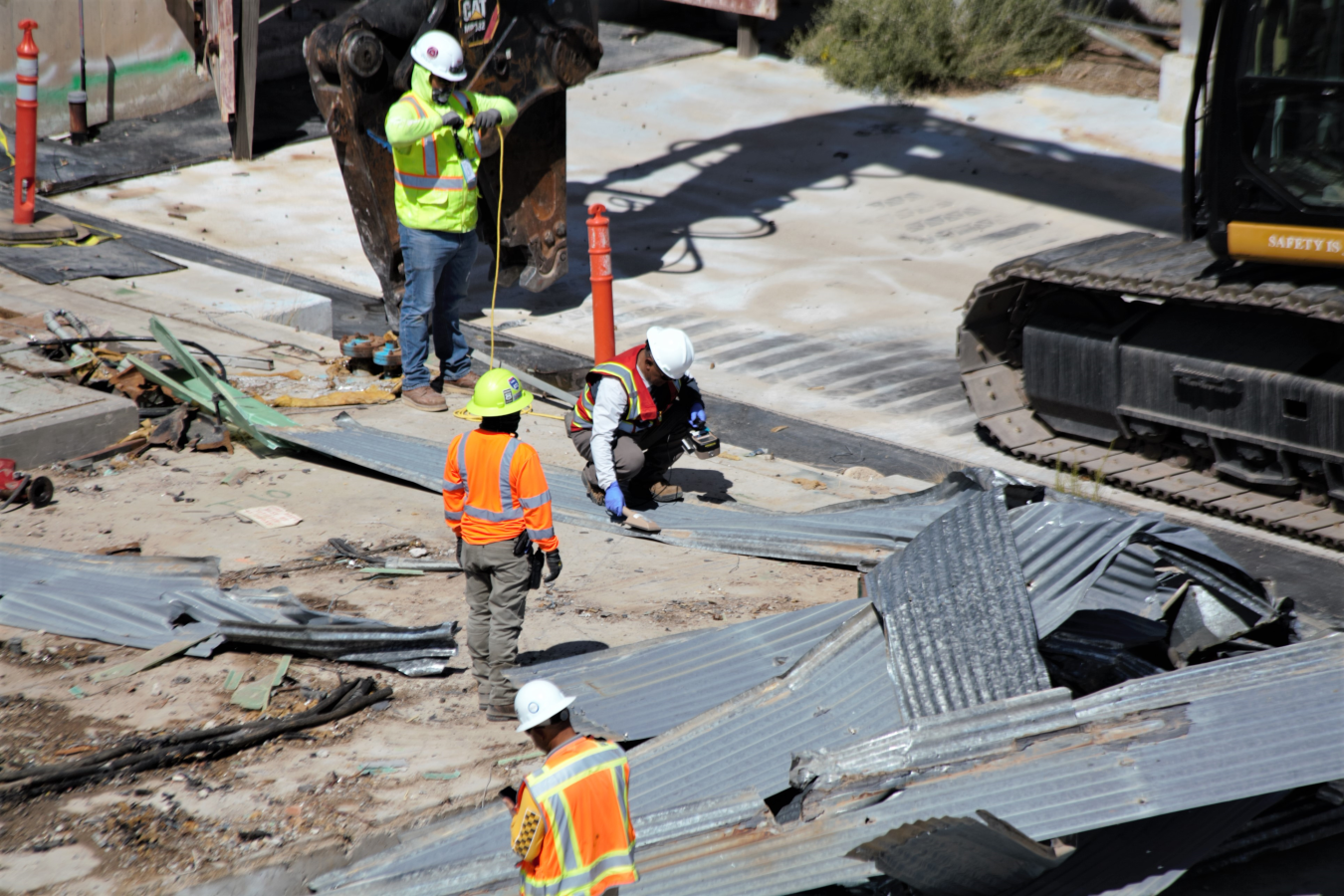 Four workers check roofing pieces after removal