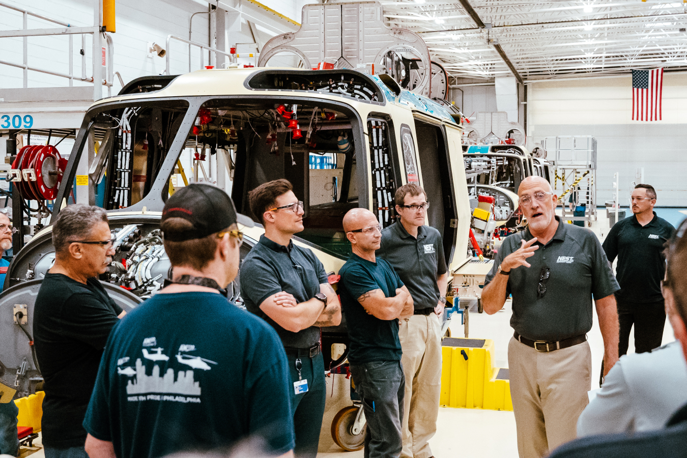 Jay Tilden speaks to about a dozen Leonard workers on the factory floor. A helicopter under construction is to his side