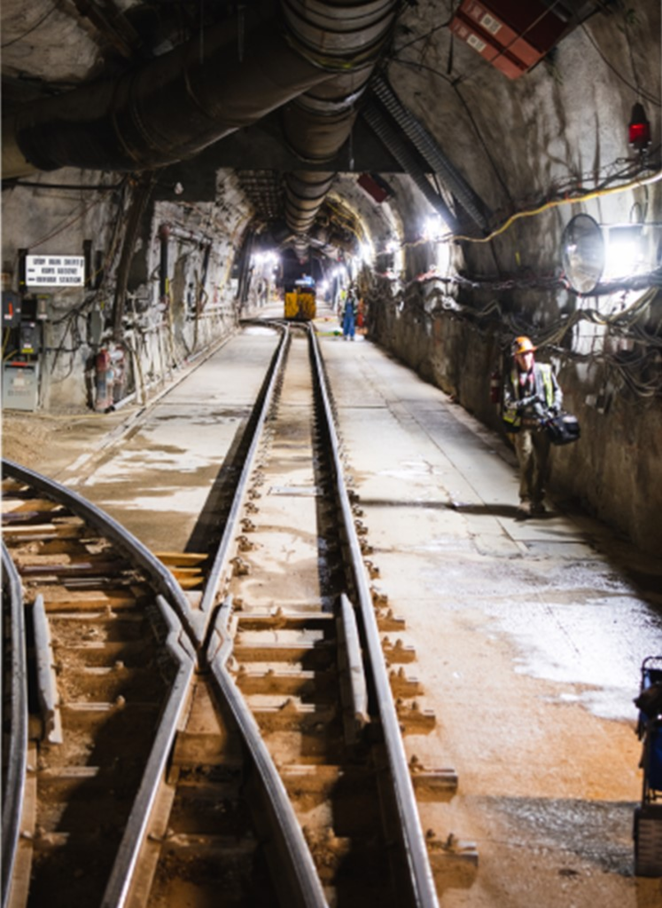 A photo showing the inside of a tunnel. Steel tracks lead into the distance.