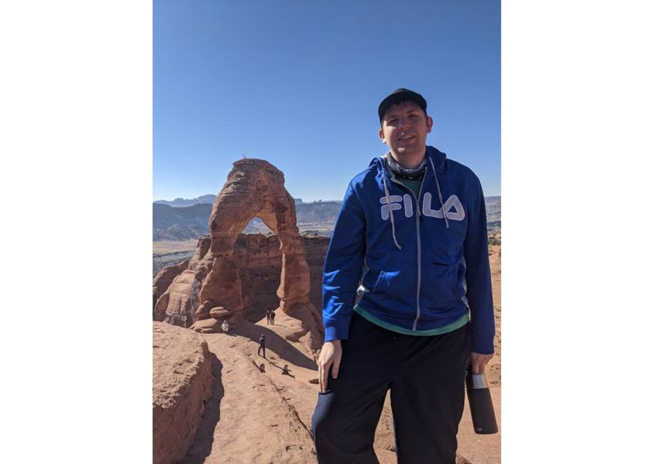 Alex Holt standing in front of stone arch in desert 