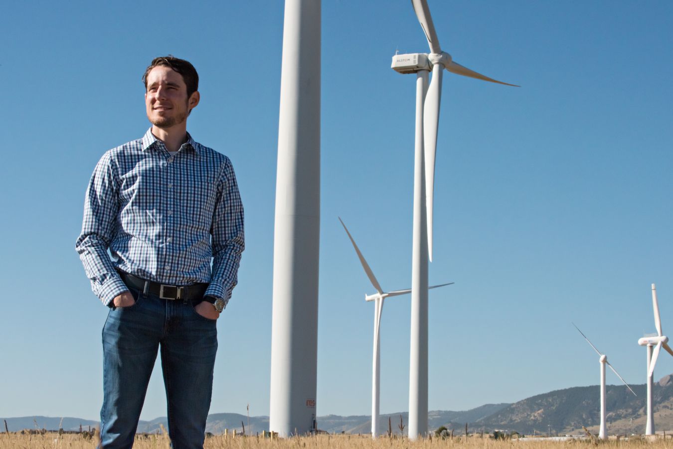 Man stands in front of a wind farm. 