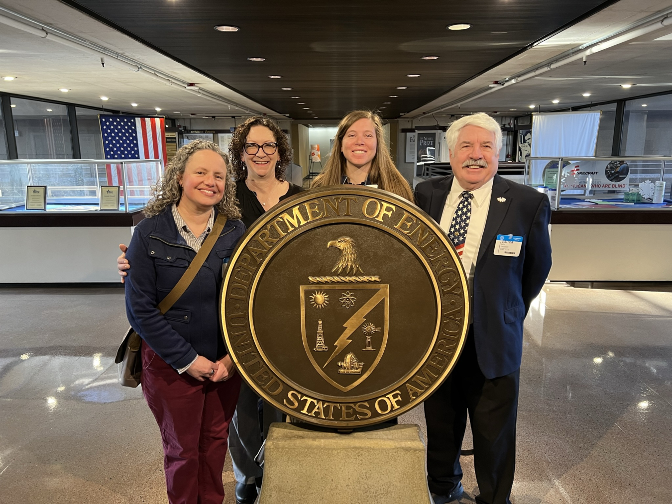 four people pose around the department of energy seal