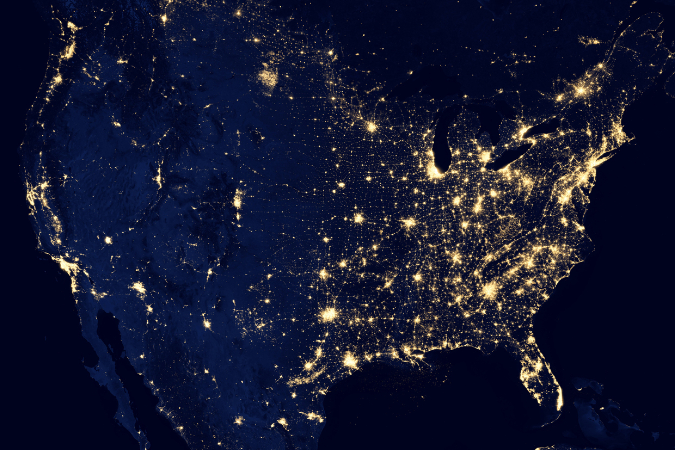 Satellite image of the United States at night with points of light emanating from the cities