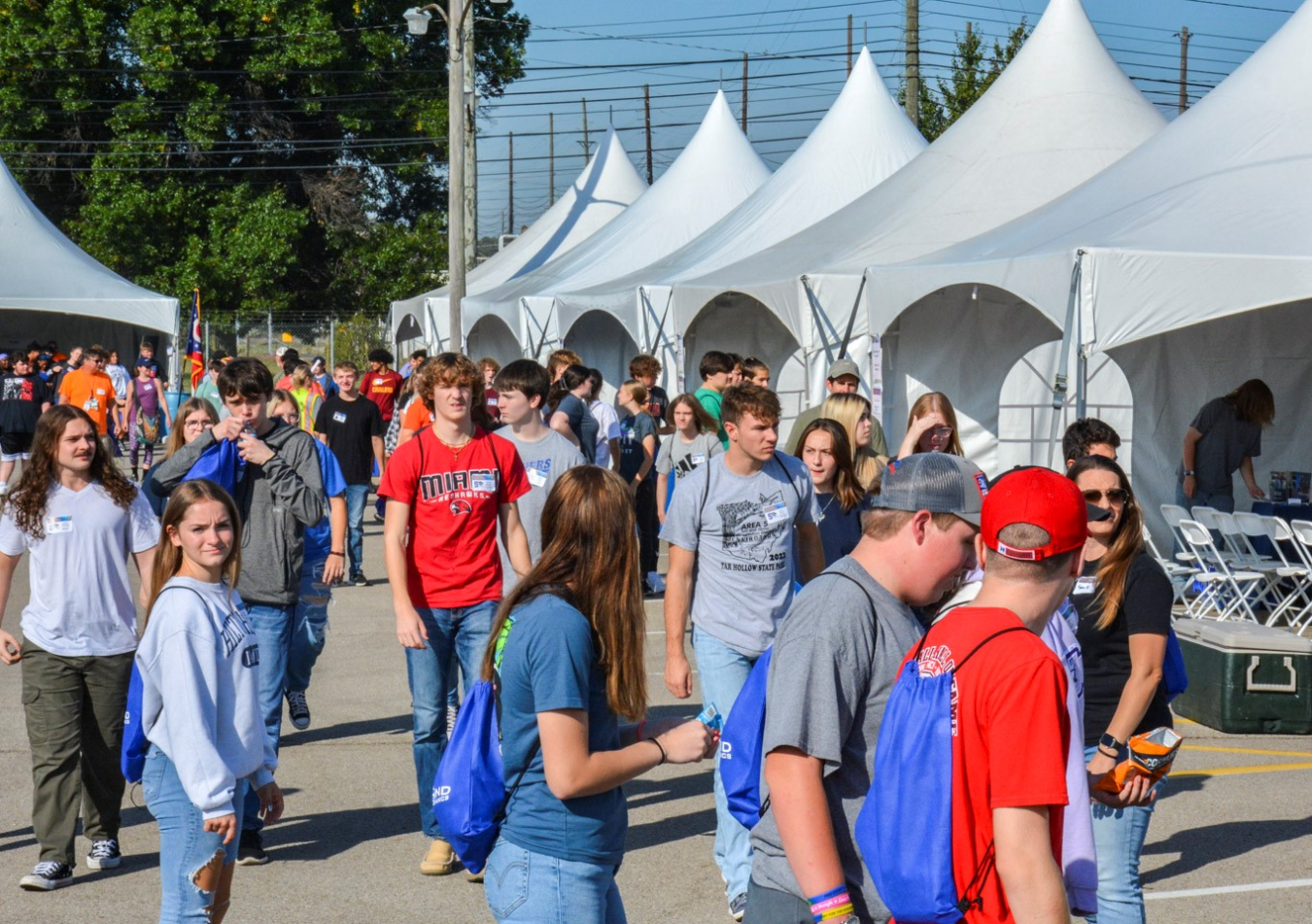 A walkway between big white tents filled with people 