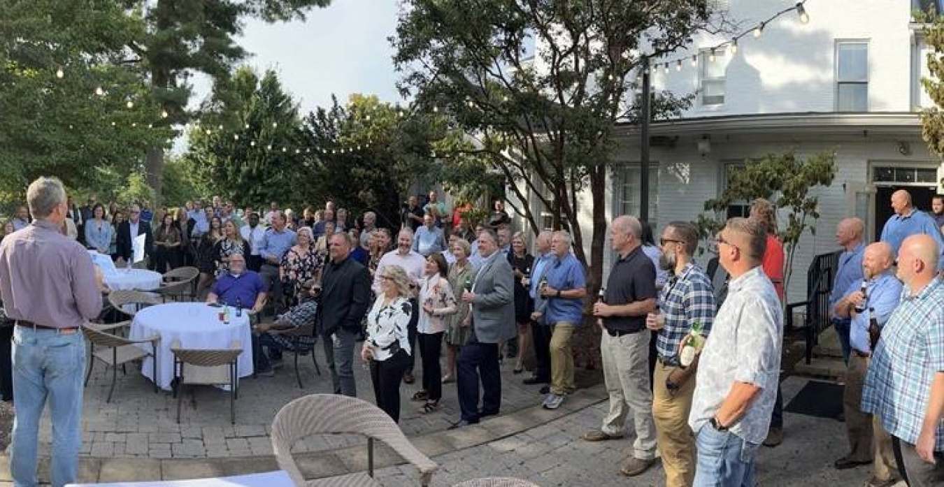 Speaker addresses group of people gathering outside.