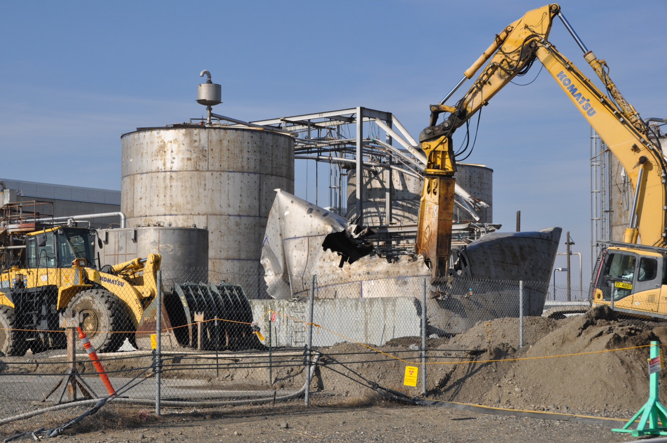 Machine with long arm performing demolition on old building.