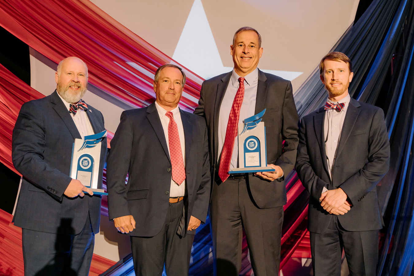 Four men with two holding award certificates.