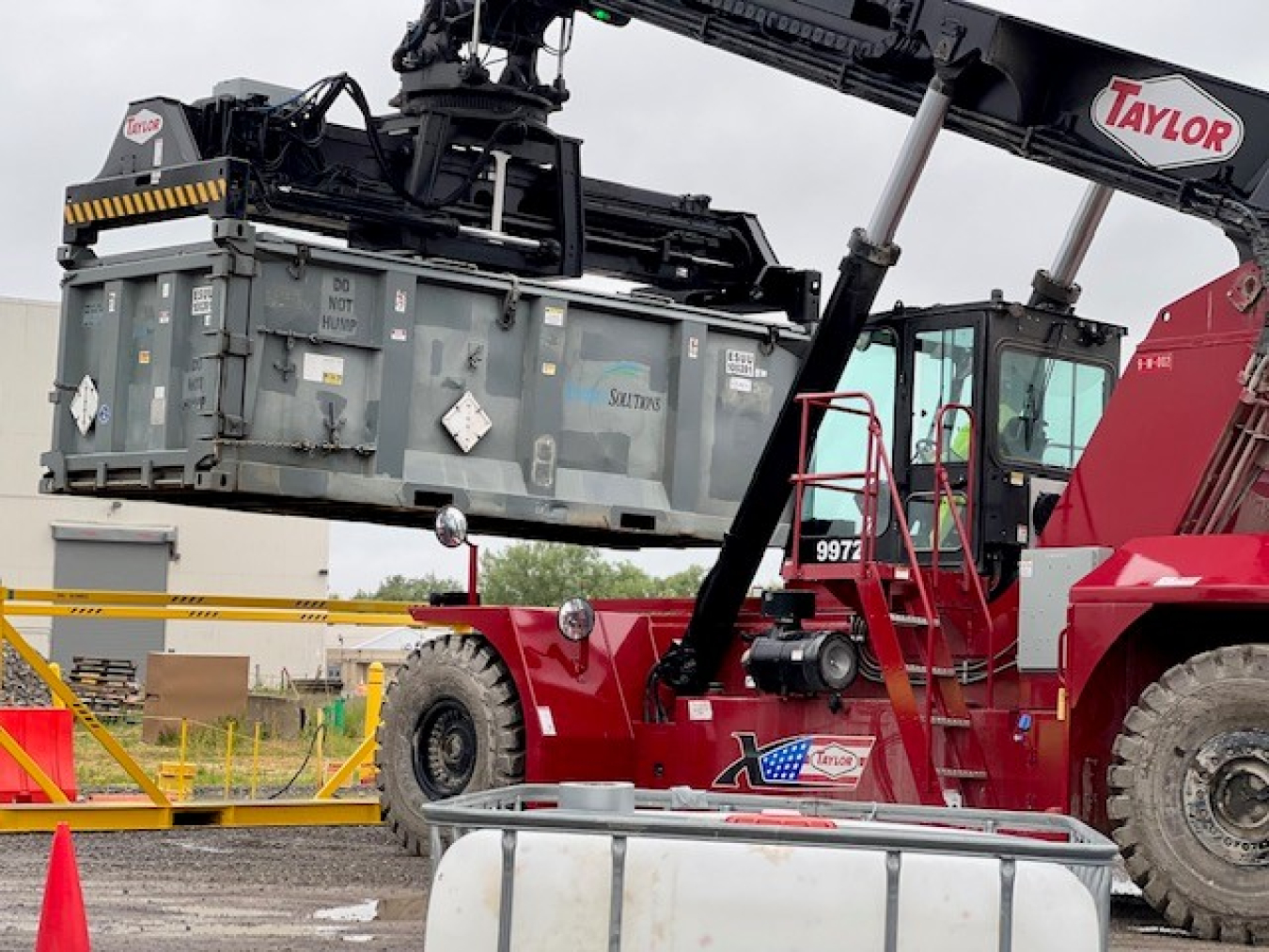 Machine with crane lifts large container in the air 