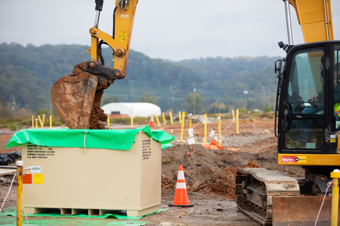 Machine unloads contaminated soil into waste container. 