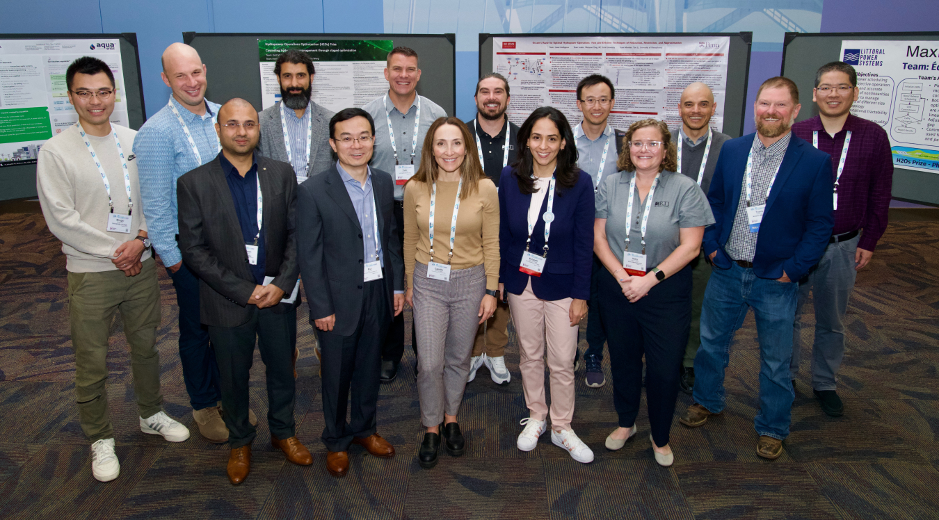 People participating in and supporting the H2Os Prize stand in front of four posters.