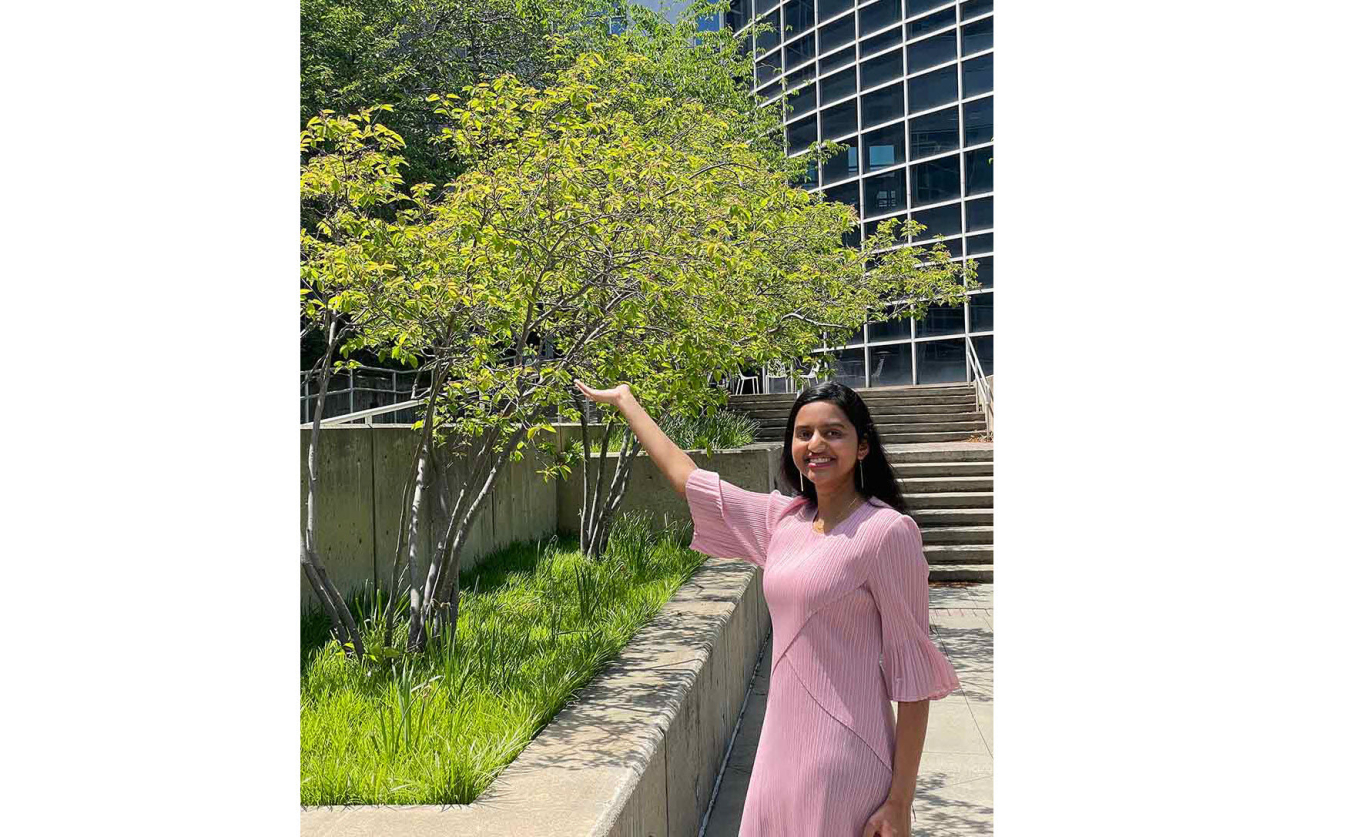 Prerana Panchumarti standing next to a tree with her arm up