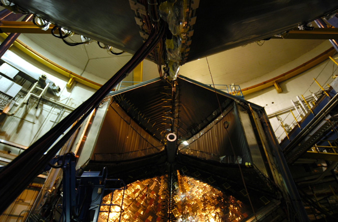 A large hexagonal machine in a lab with glowing gold light inside