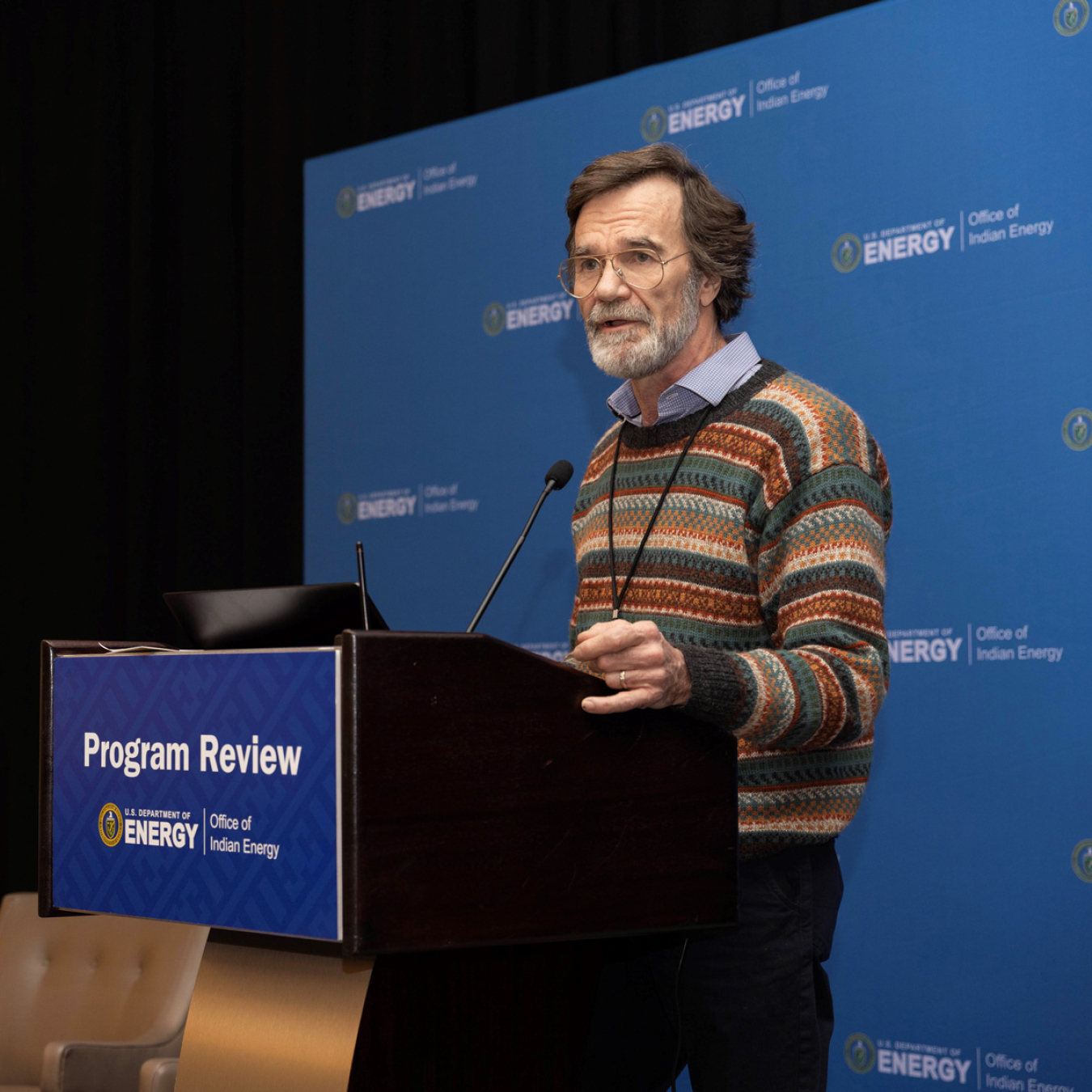 An older man speaks behind a podium.