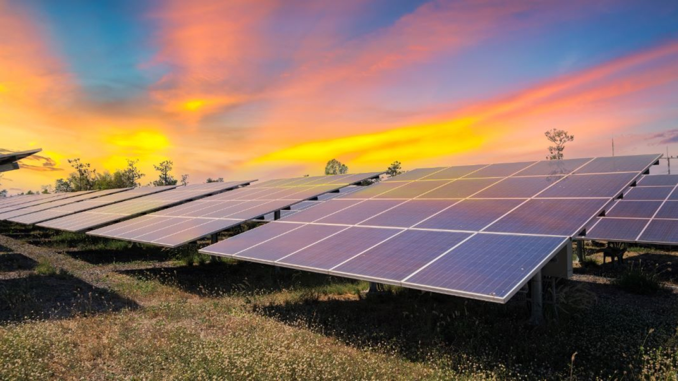 Clean energy solar panels are shown against a brilliant sunset sky in the background.