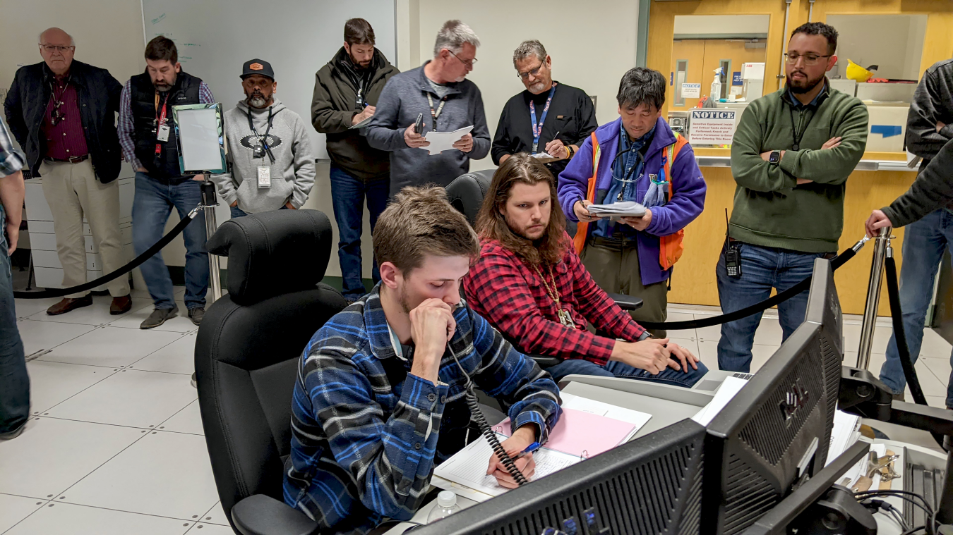 Employees sit and stand around computers