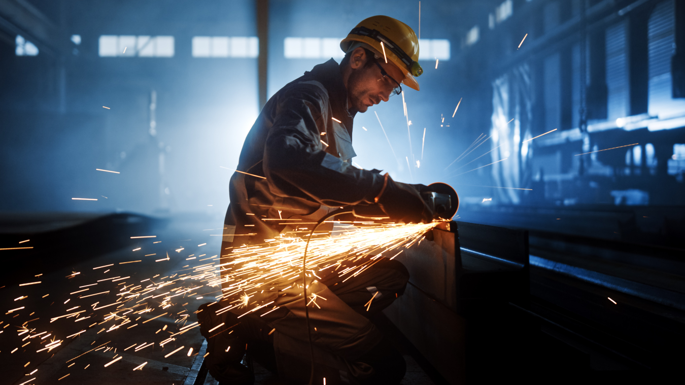 a photo of a person cutting metal  with an angle grinder. The  grinder is shooting a stream of sparks.