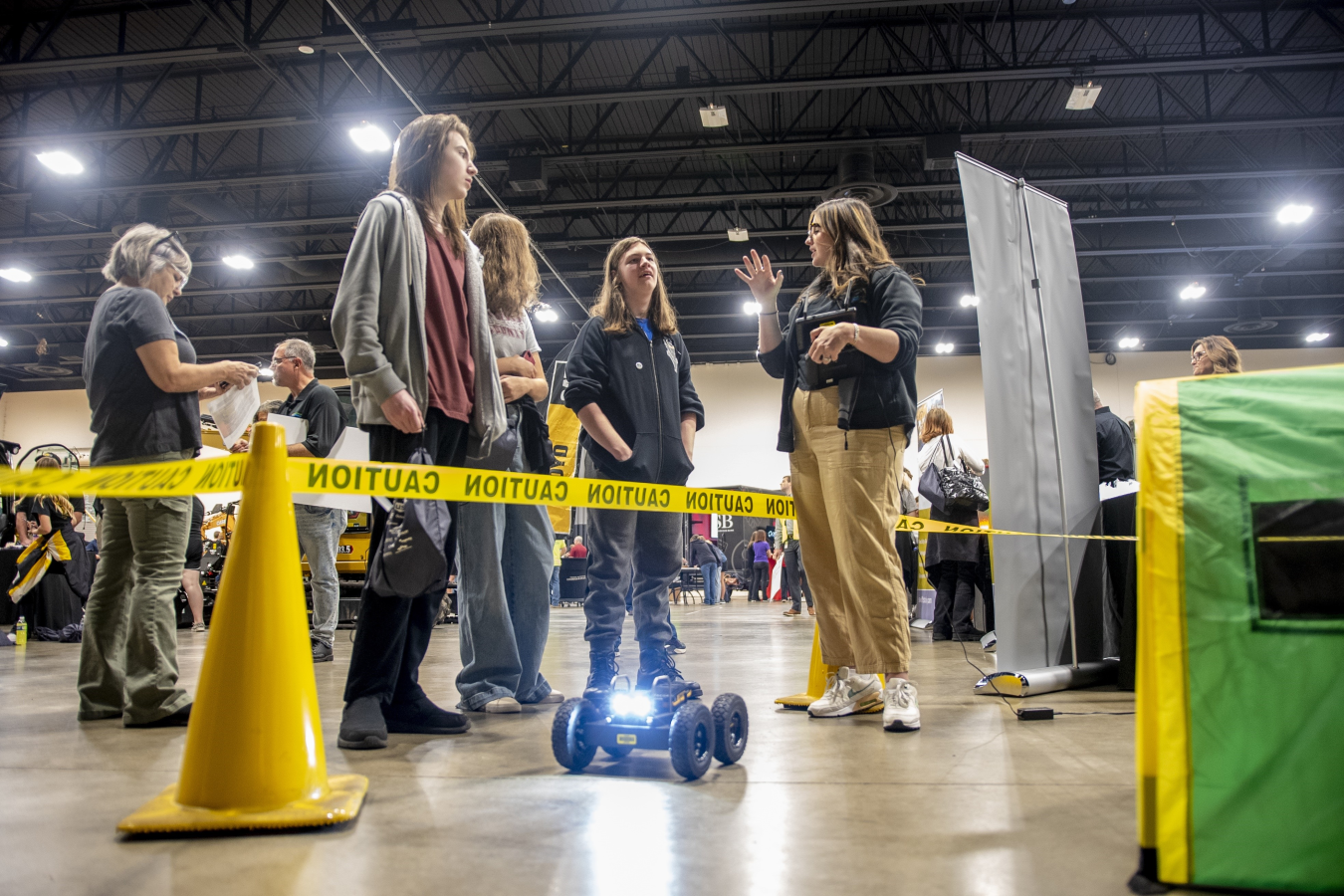 A woman demonstrates a piece of technology to a group of students