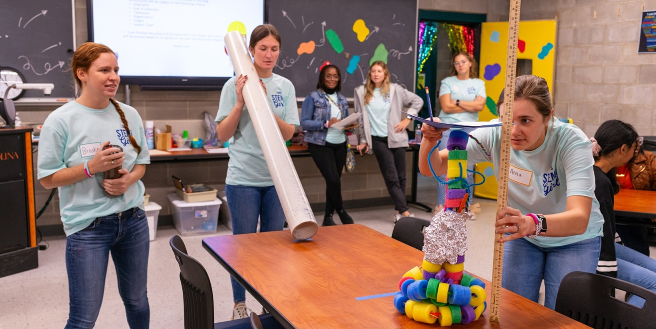 A team of girls measures the height of a structure they built