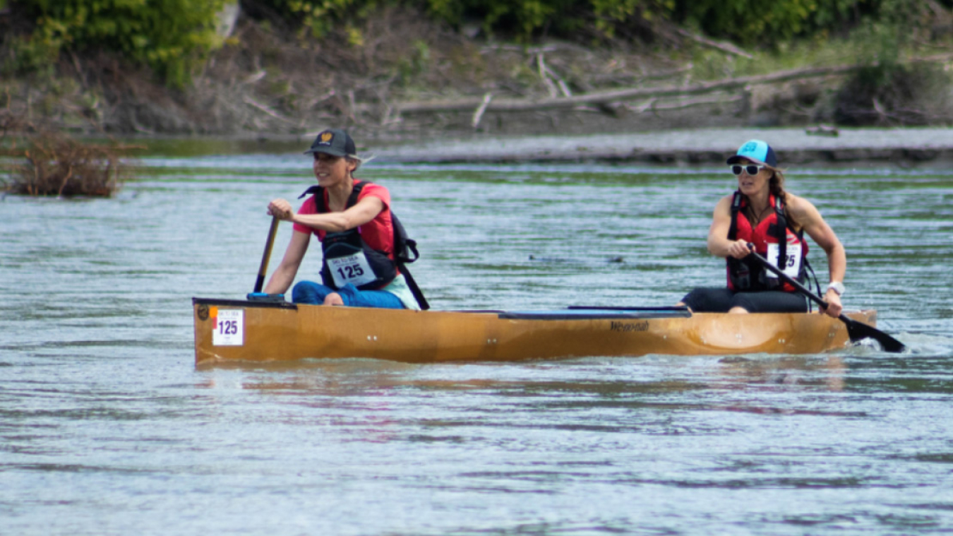 Two women row a canoe.