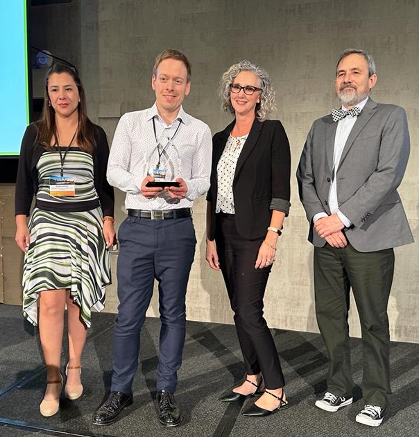 A photo of Petts holding an award with three other people flanking him.