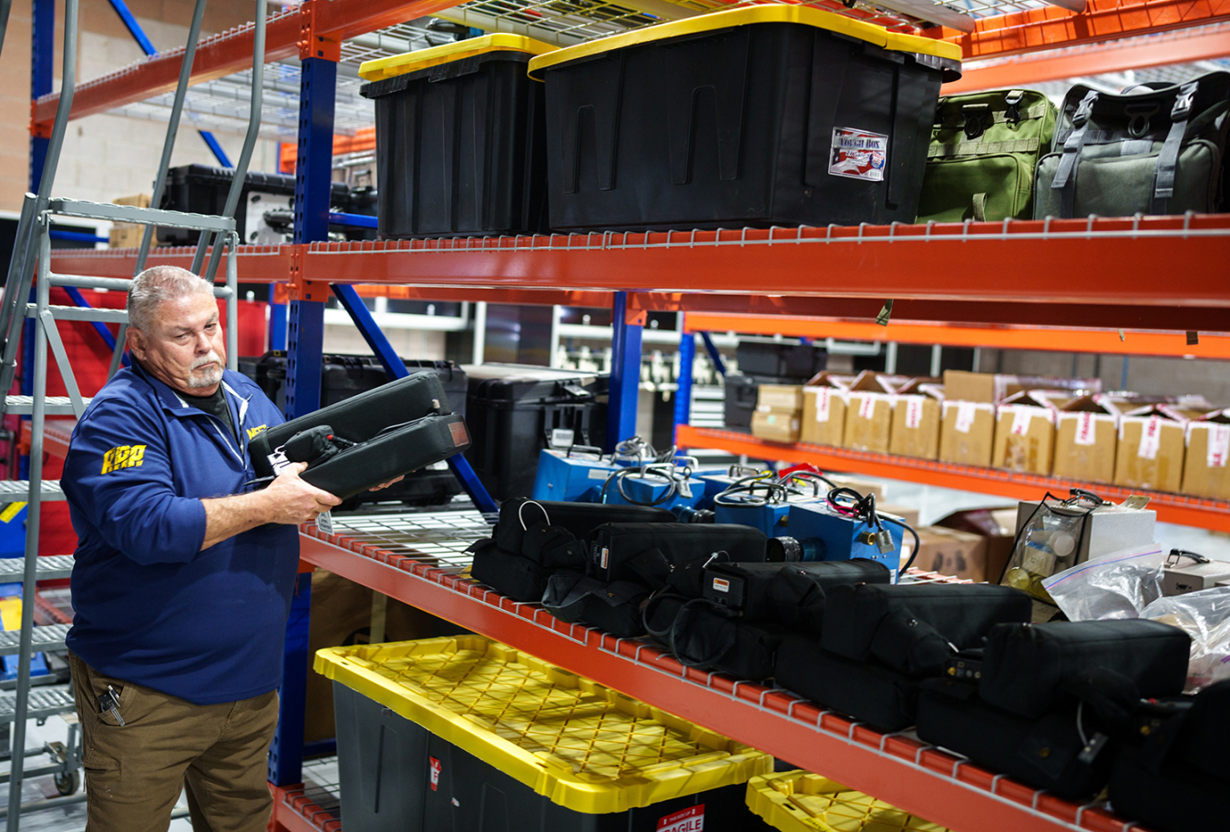 A man takes a piece of equipment off a large rack that has lots of other, similar-looking equipment on it.