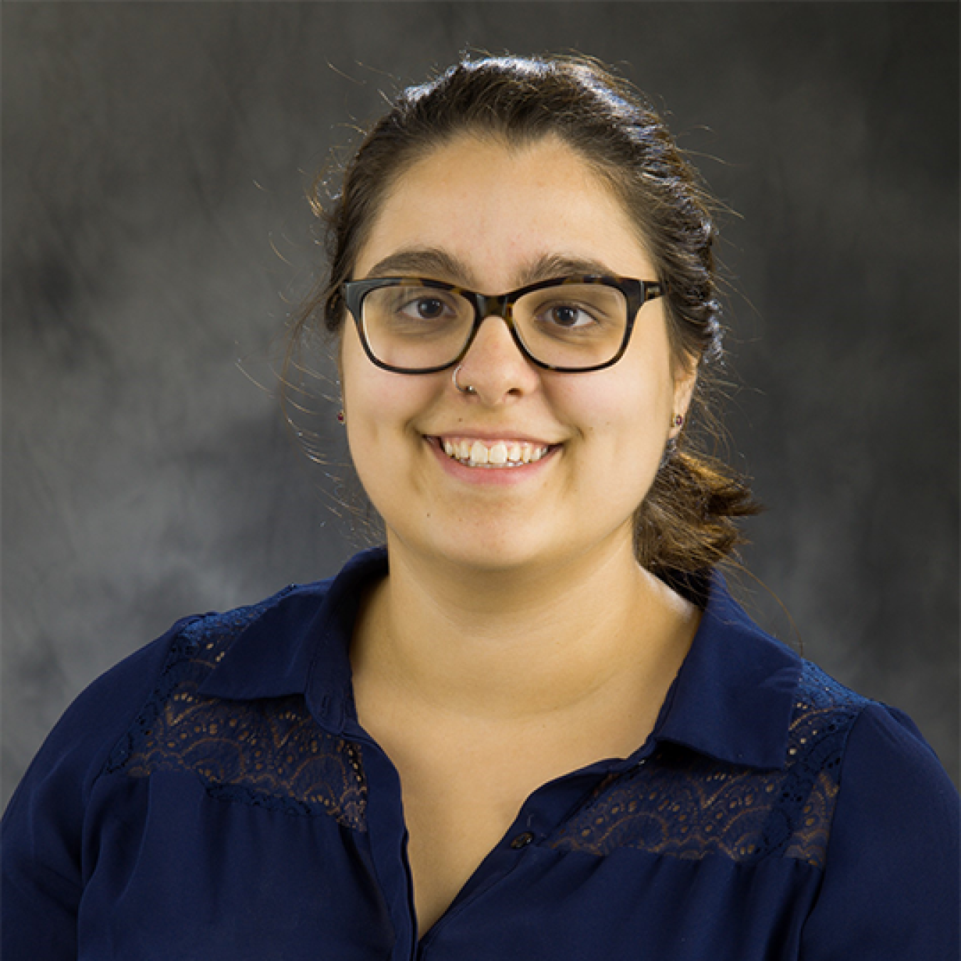 Anne Marie Esposito, smiling, wearing glasses and a collared top.