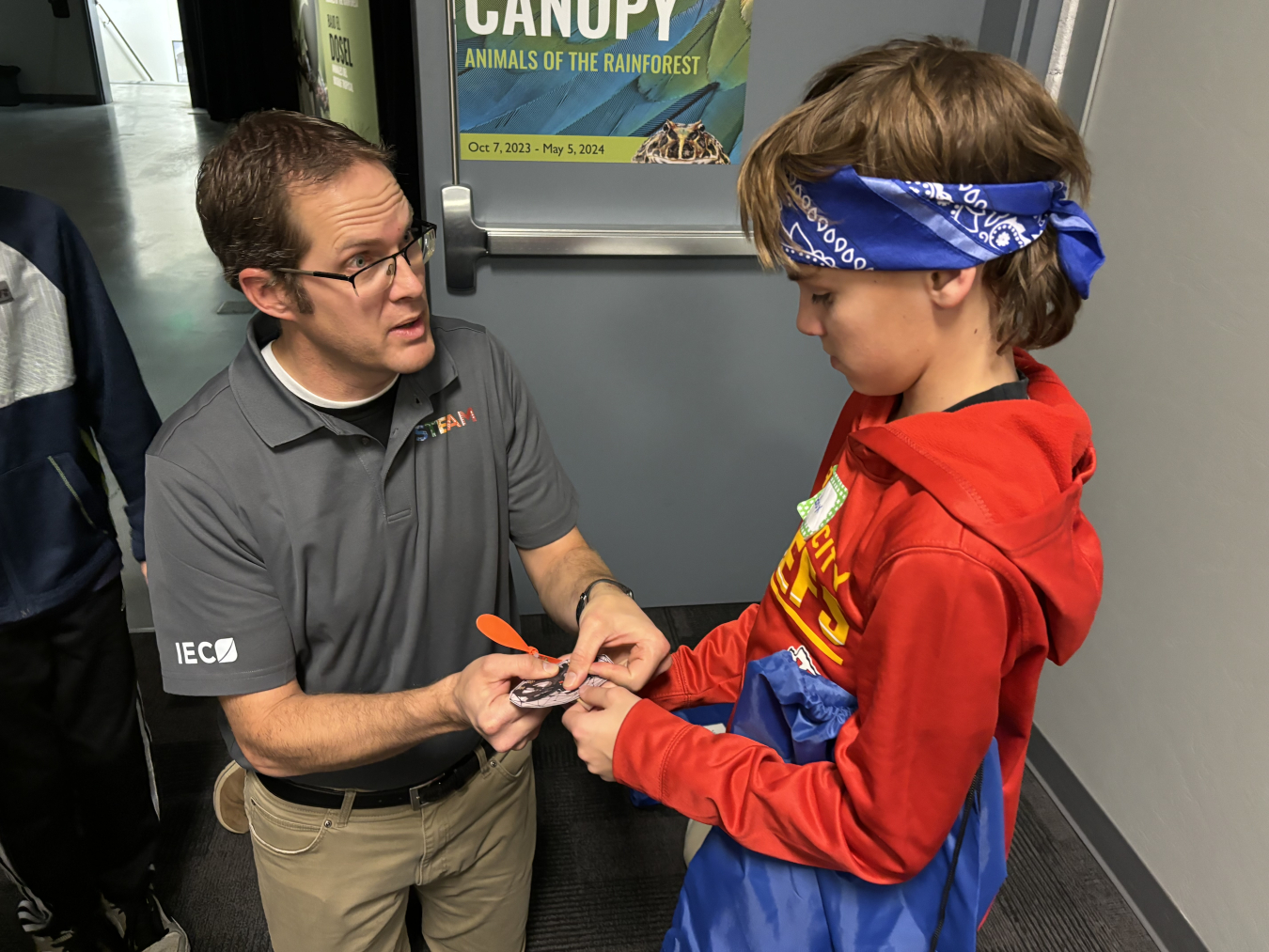 An employee helps a student with their rubber band drone