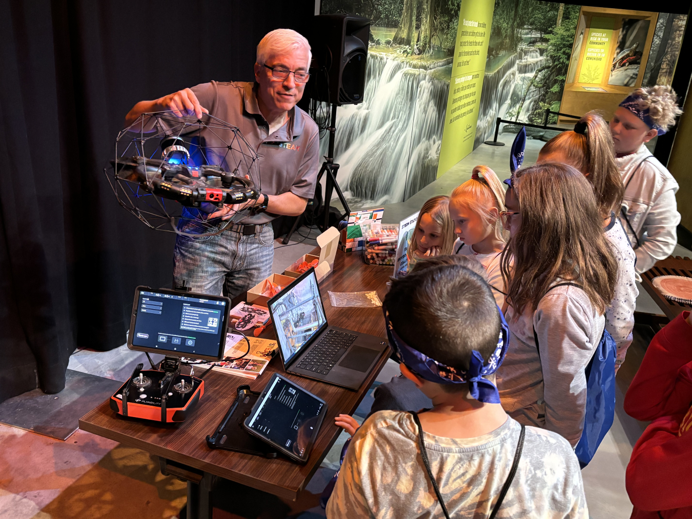 A man stands behind a table and teaches students about science