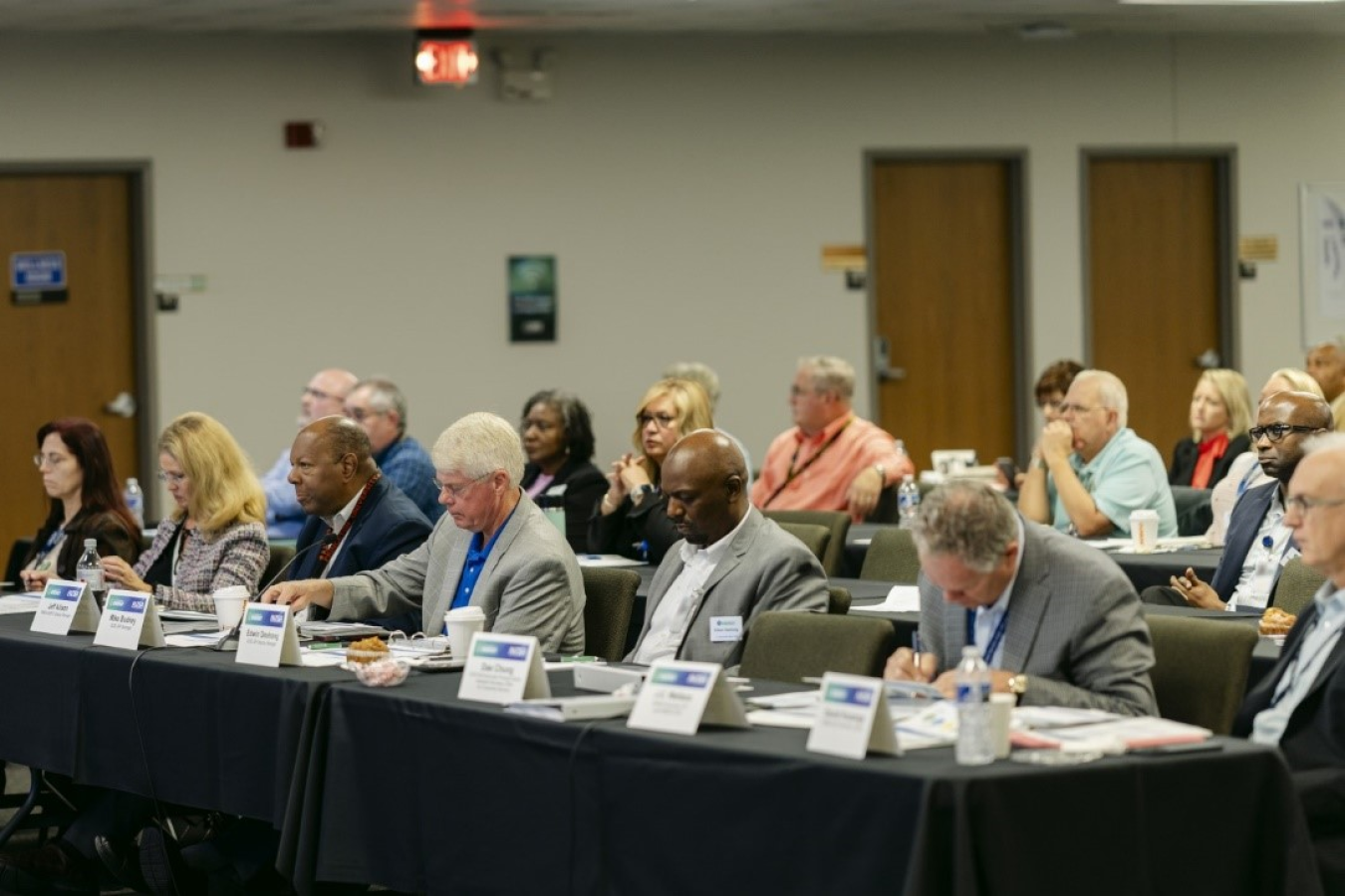 A panel of professionals sit at a long table