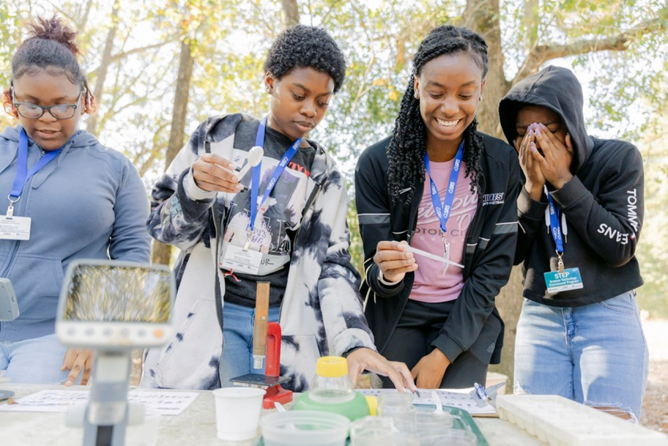 4 students stand around a table and use a microscope